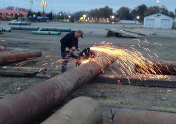 Worker cutting industrial pipe with sparks